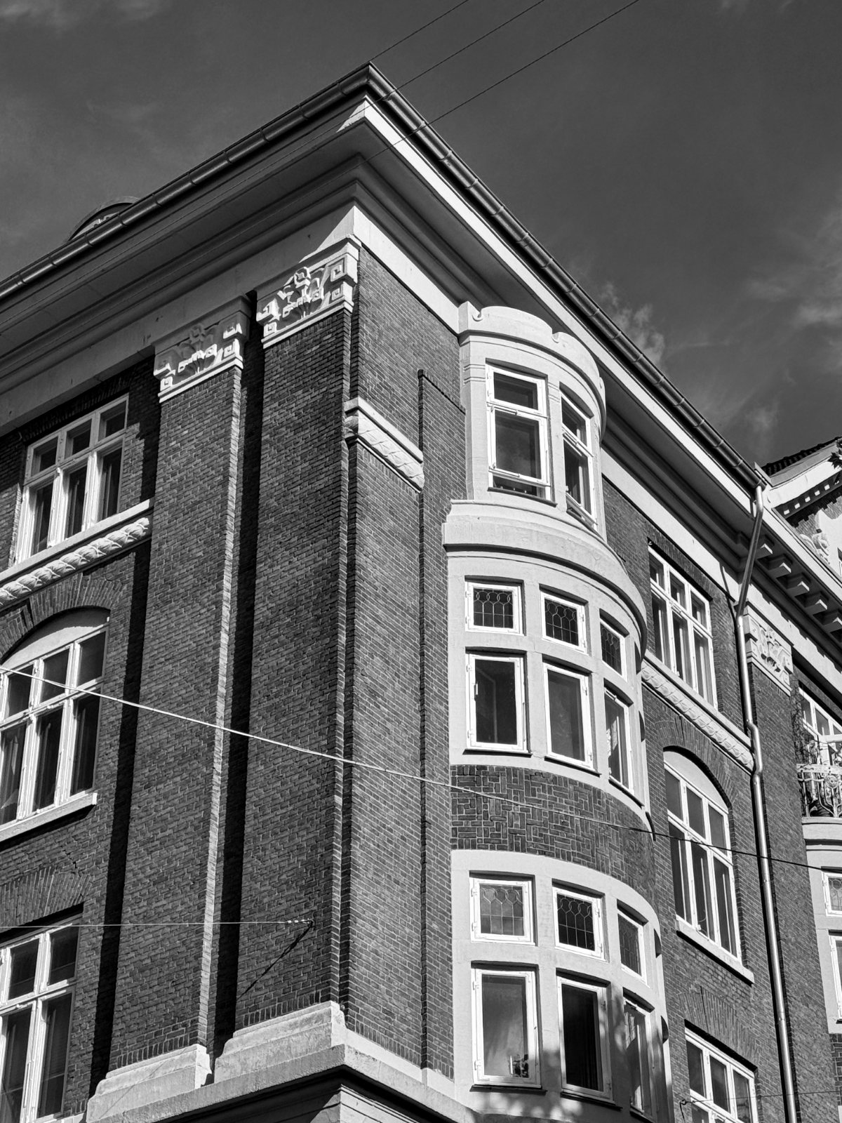 Bay window on a red-brick building — black and white